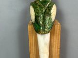 statue of a green parrot sitting on top of a piece of wood