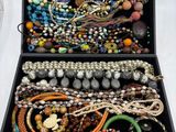 une boîte noire remplie de bijoux divers posée sur une table