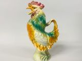 une figurine en céramique représentant un coq sur fond blanc