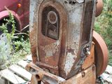 a rusted out machine sitting on a pallet next to a car