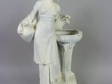une statue blanche représentant une femme tenant un oiseau dans la main