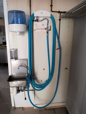 un tuyau bleu fixé au mur à côté d'un distributeur d'eau