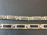 a close up of two metal bracelets on a black leather surface