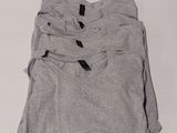 three pairs of grey t - shirts sitting on top of a white table