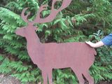 un homme qui se tient à côté d'un cerf en métal