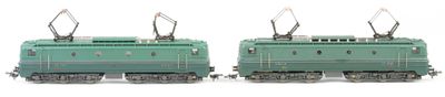 two green trains sitting side by side on a white surface