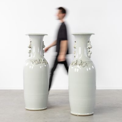deux grands vases posés par terre devant un homme