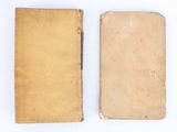 two old books sitting on top of each other on a white surface