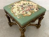 an ornately decorated foot stool with a green cushion