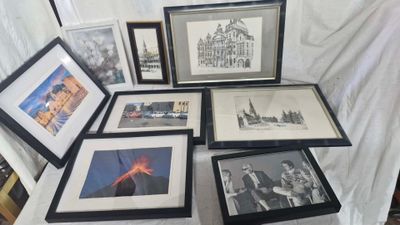 many framed pictures on a table with a white table cloth