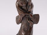 an image of a bronze statue of a woman with a fan