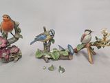 three figurines of birds sitting on a branch of a tree