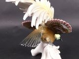 a figurine of a bird that is sitting on a flower
