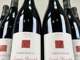 six bottles of red wine are lined up on a table