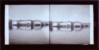 une photo en noir et blanc d'une rivière avec des bâtiments en arrière-plan