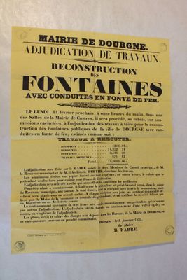 une affiche jaune accrochée au mur d'un immeuble sur lequel est apposée une pancarte