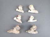 plusieurs petites figurines en céramique représentant des chaussures et des chapeaux, posées sur une surface grise