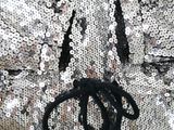 the back of a silver sequinned jacket with a black tie