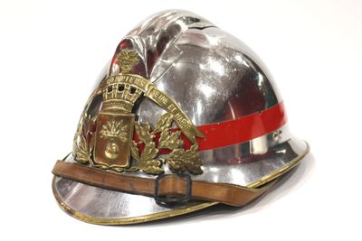 un casque de pompier argenté orné d'un ruban rouge
