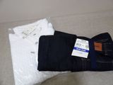 two pairs of jeans and a white shirt on a bed