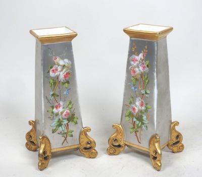 une paire de vases décorés de fleurs, posés sur une surface blanche