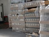 Des cartons d'eau sont empilés sur des palettes dans un entrepôt