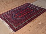 un tapis rouge et noir posé sur le sol d'une pièce