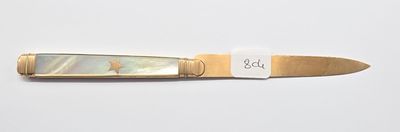 un petit couteau muni d'une étiquette, posé sur une surface blanche