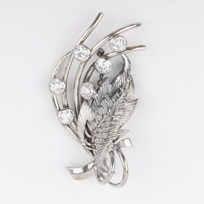 Gros plan sur une broche ornée de feuilles et de diamants sur fond blanc
