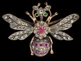 un gros plan sur une broche en forme d'abeille ornée de pierres roses, vertes et blanches