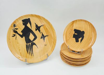 des assiettes en bois ornées d'une image représentant une femme et des oiseaux