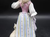 une figurine représentant une femme avec un chien, posée sur un fond noir