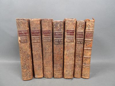 six old books are lined up in a row on a gray surface