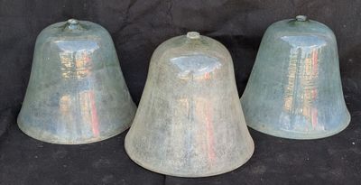 trois cloches posées les unes à côté des autres sur une surface noire