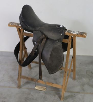 une selle noire posée sur un support en bois dans une pièce