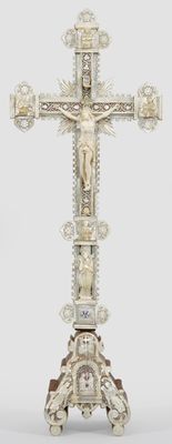 une croix en argent surmontée d'un crucifix, posée sur un socle