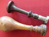 two antique wooden handles on a red surface