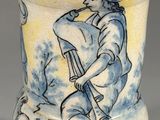a blue and white vase with a man and a dog on it