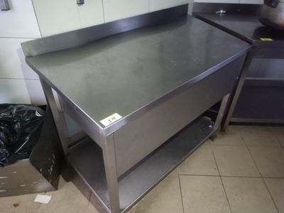 une table de travail en acier inoxydable dans une cuisine, avec un sac poubelle