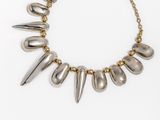 a gold and silver necklace with spikes on a chain