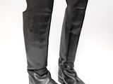 une paire de bottes en cuir noir posées sur une surface blanche, sur fond blanc