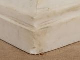 a close up of a corner of a white vase on a table