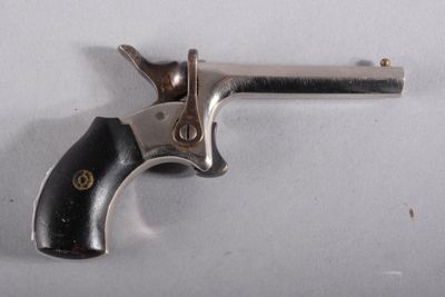 un vieux revolver argenté avec une crosse noire sur un fond blanc
