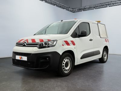 une camionnette Citroën rayée de rouge et de blanc, garée dans un garage