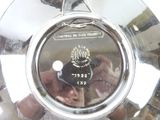 a close up of a silver clock with a person taking a picture