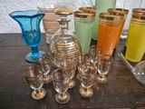 many different colored glass vases and glasses on the table