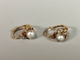 two gold rings with pearls on them sitting on a white surface