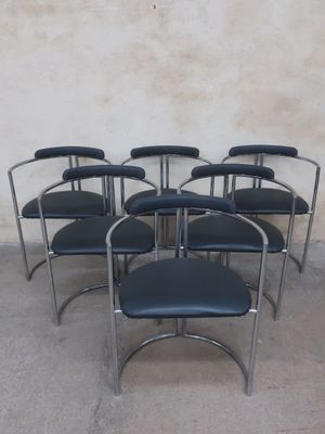 six black leather chairs in a row against a white wall