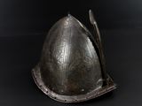 an old helmet is sitting on a black surface with a spoon