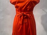 an orange dress on a mannequin stand with a white background